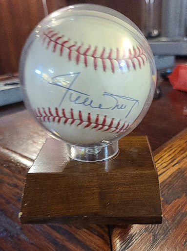 Autographed baseball with signature on Official National League Rawlings baseball, displayed on wooden base