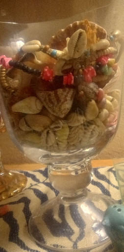 Glass footed compote or apothecary jar filled with decorative seashells and coral