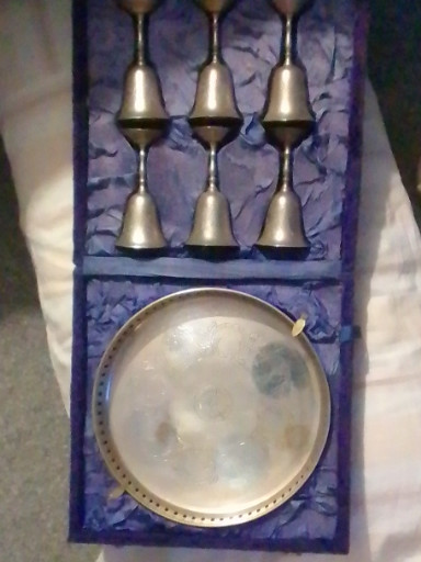 Brass serving set late 19th century. With 6/goblets shaped like bells and a round tray, all decorated with a floral design engraved or etched onto the metalware. beautifuly presented in a purple velvet-lined case.