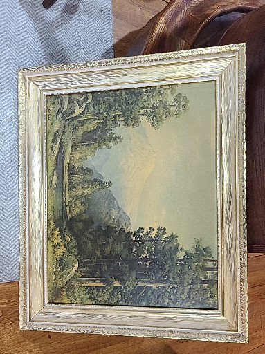 Vintage framed landscape print depicting a mountain stream scene with trees and cottage