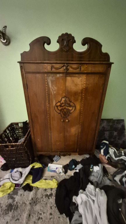 Wooden armoire with carved decorative crest and inlay details
