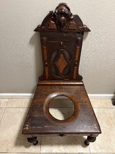 Carved walnut chaise percée (commode chair) with ornate back panel and burl wood inlay