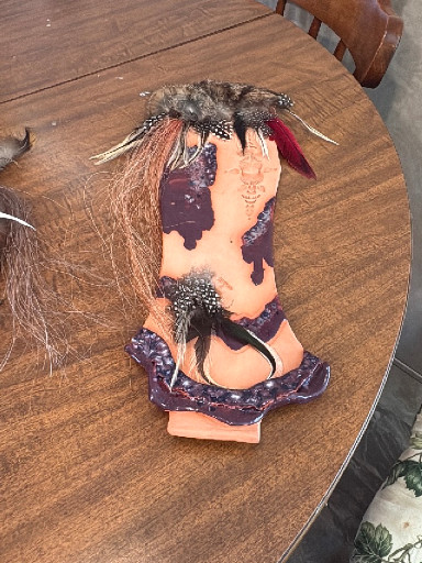 Folk art doll with mixed media construction including fabric, feathers, and hair