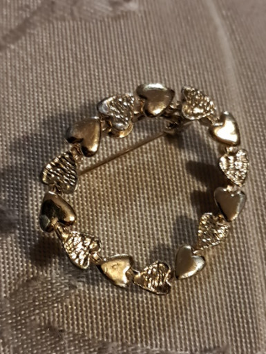Gold-tone metal brooch titled 'Circle of Hearts' by Gerry's