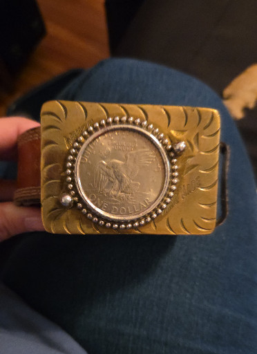 Gold-tone belt buckle featuring an Eisenhower Dollar coin with eagle design