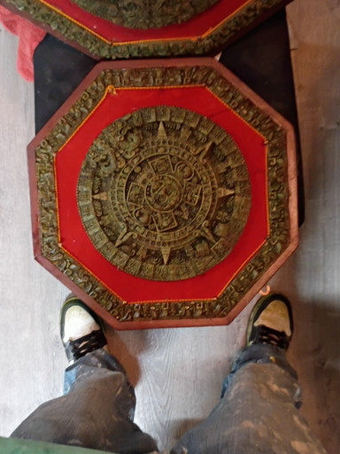 Reproduction of Aztec Sun Stone calendar in crushed malachite and resin with red velvet backing