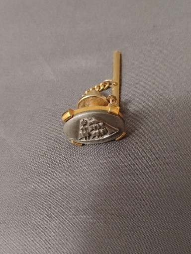 Gold-tone tie tack with carved sailing ship motif