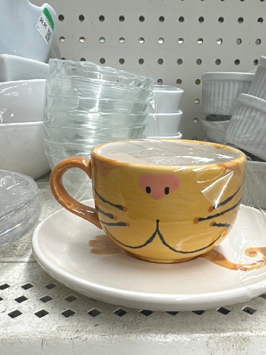 Ceramic mug with saucer featuring a yellow cat design