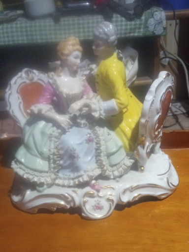 Porcelain figurine depicting a Victorian couple in elaborate dress with lace detailing