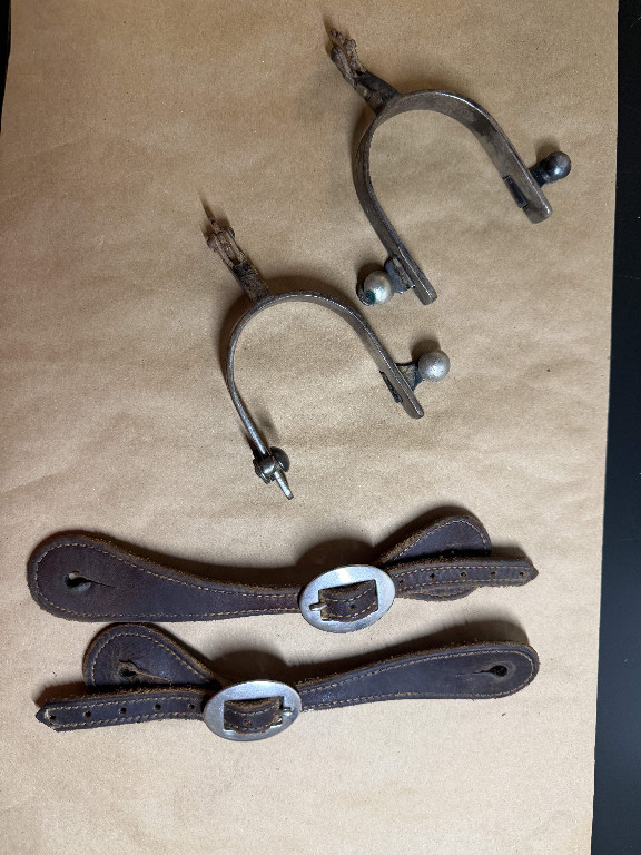 Metal riding spurs with leather straps