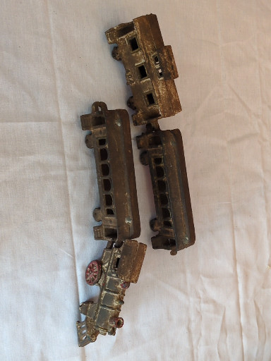 Cast iron toy train set comprising a locomotive and three passenger cars, likely American-made