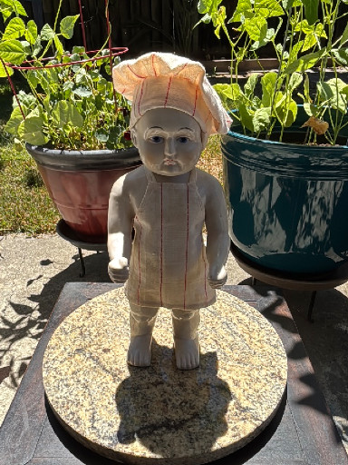 Concrete garden statue of a child figure in chef's attire