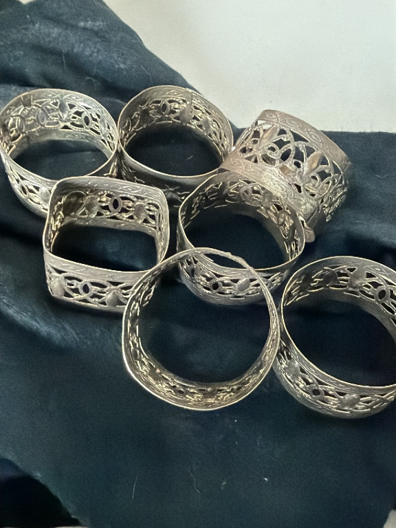 Set of seven silver-tone metal napkin rings with openwork fleur-de-lis filigree design