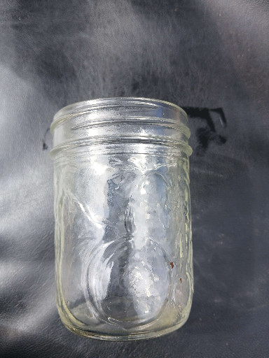 Glass jar with embossed fruit design, likely Ball Mason jar