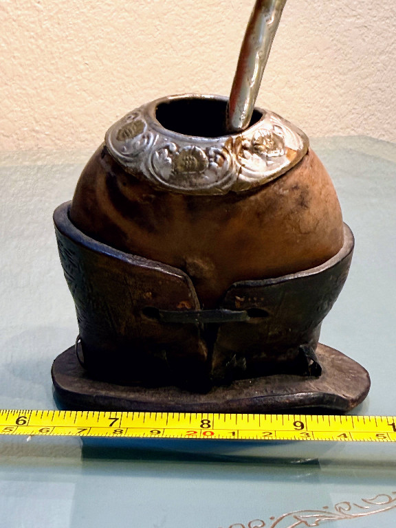 Traditional mate gourd (calabash) with silver-plated rim and bombilla straw, mounted on leather stand