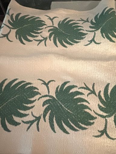 Barkcloth fabric featuring tropical palm frond motif in green on cream background