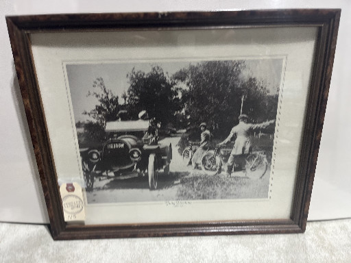 Framed black-and-white photograph titled 'Giving Directions' depicting early motorcyclists and an automobile, circa 1912