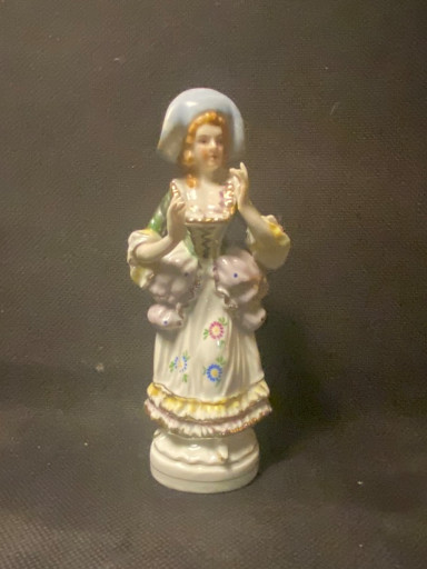 Porselein beeldje van een jonge vrouw met bloemen en een mand