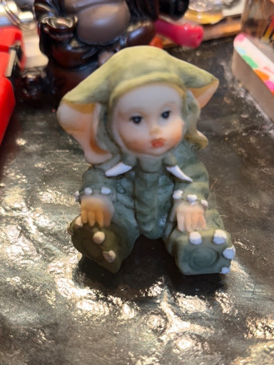 Ceramic figurine of a pixie elf child sitting with a snail and mushroom