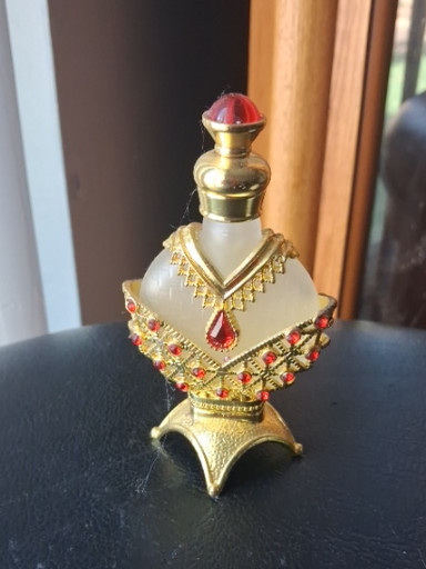 Decorative jeweled perfume bottle with ornate metal filigree and rhinestone embellishments