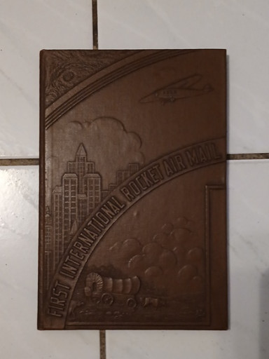 Leather-bound commemorative book titled 'First International Rocket Mail' from 1936, complete with original rocket mail stamps