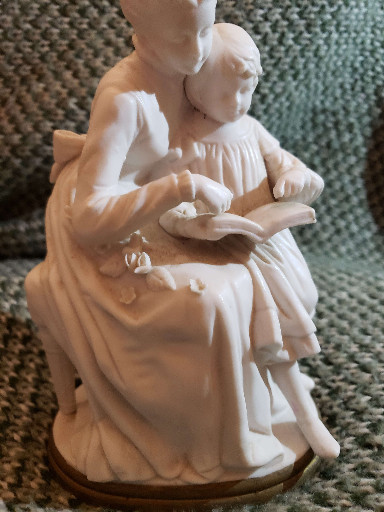 Porcelain figurine depicting a mother and child reading together