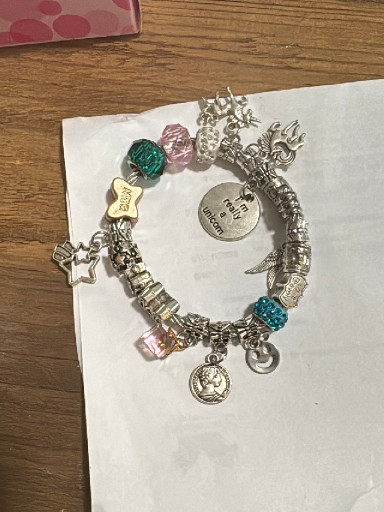 Silver-tone charm bracelet with mixed decorative charms including piano, snake, disco ball, and heart motifs