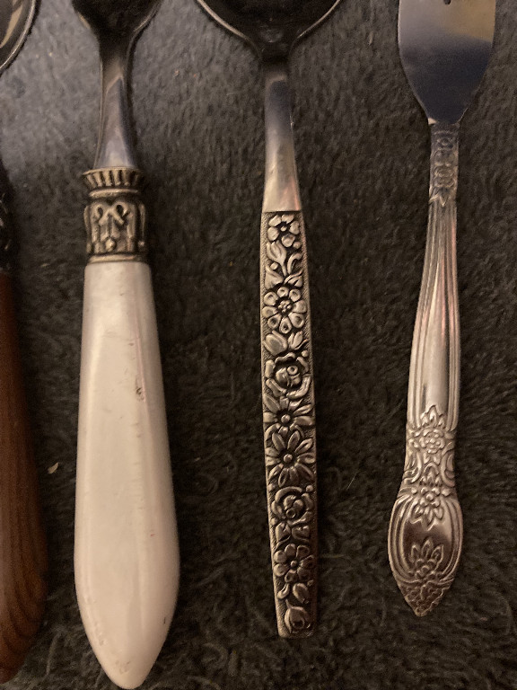 Vintage stainless steel flatware set featuring floral-patterned handles, including pieces from Oneida Malibu pattern and similar decorative patterns