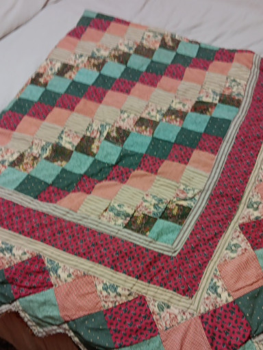 Handmade patchwork quilt with floral and geometric patterns in burgundy, green, and pink tones