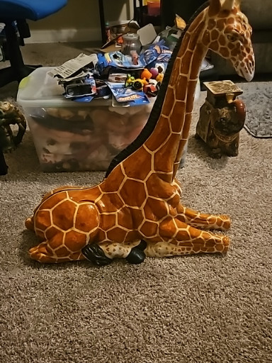 Ceramic giraffe sculpture in seated position with hand-painted glaze