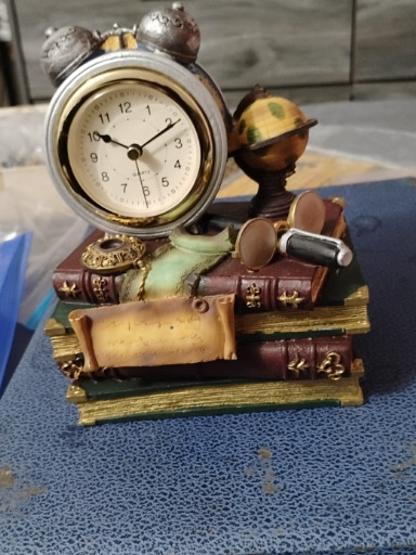 Resin decorative desk clock with stacked vintage travel-themed elements including suitcases, globe, and books