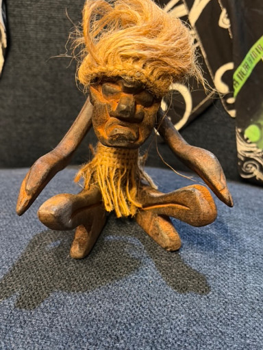 Hand-carved wooden tiki figure with natural fiber hair and skirt