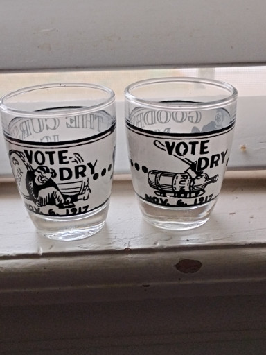 Pair of vintage glass shot glasses with Prohibition-era themed graphics 'Vote Dry' and 'Goodbye Mr. Booze'