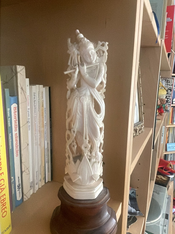 Scultura in osso bovino raffigurante la divinità Krishna su base in legno