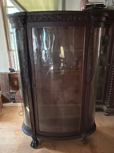 Oak curved glass china cabinet with carved lion head details and claw feet, American Victorian style