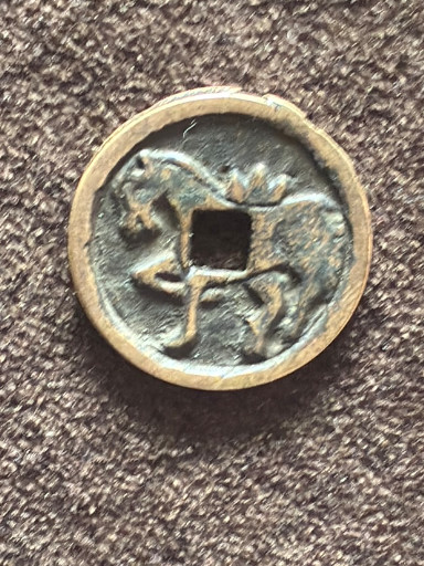 Bronze square-hole coin with decorative motif, likely a Chinese charm or commemorative piece