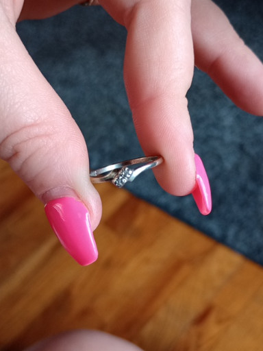 White gold or platinum engagement ring with a small round brilliant-cut diamond in a bypass or twist setting