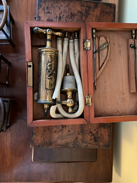 Mahogany-cased medical pump or enema apparatus with glass reservoir and brass fittings, likely by Maw & Son or similar English medical instrument maker