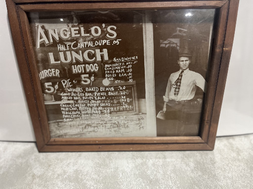 Framed vintage photograph titled 'Angelo's Lunch' showing a 1930s-era restaurant storefront with menu board