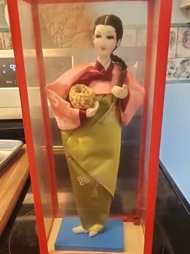 Vintage Korean traditional cloth doll in hanbok holding a janggu drum