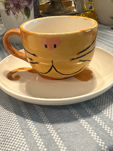 Ceramic novelty mug with saucer featuring a cat face design