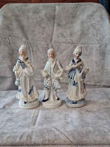 Porcelain figurines depicting three ladies in 18th-century Rococo-style dress with blue and white decoration
