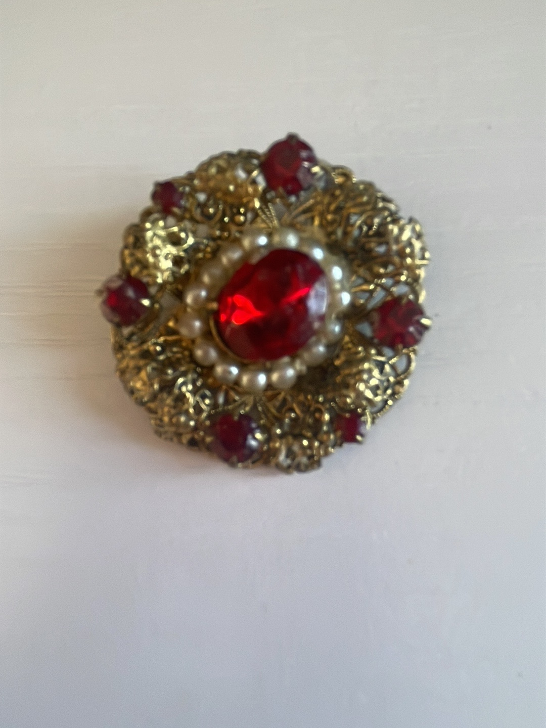 Vintage gold-tone filigree brooch with red glass stones and faux pearls