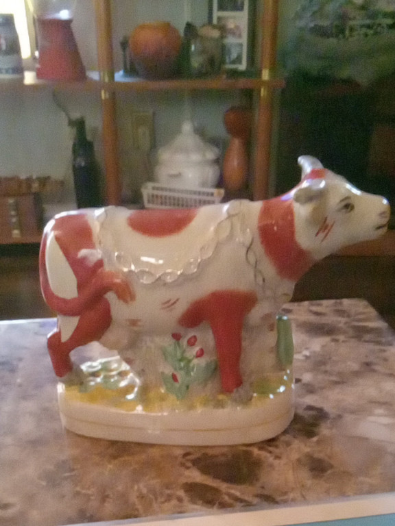 Ceramic cow figurine in Staffordshire style with red and white coloration