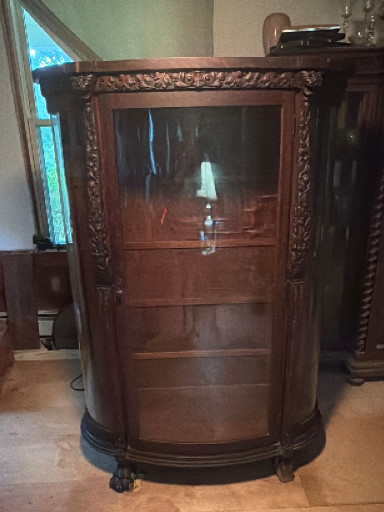 Oak bow-front china cabinet with carved lion head details and claw feet, circa early 1900s
