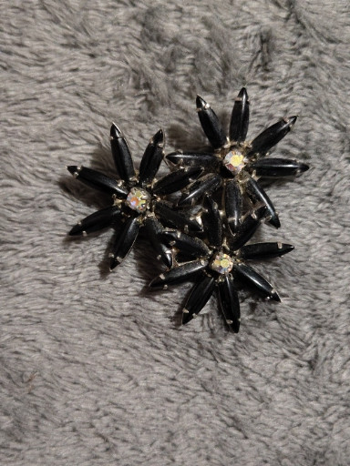 Vintage costume jewelry brooch featuring black navette-shaped stones with aurora borealis rhinestone centers in a floral cluster design