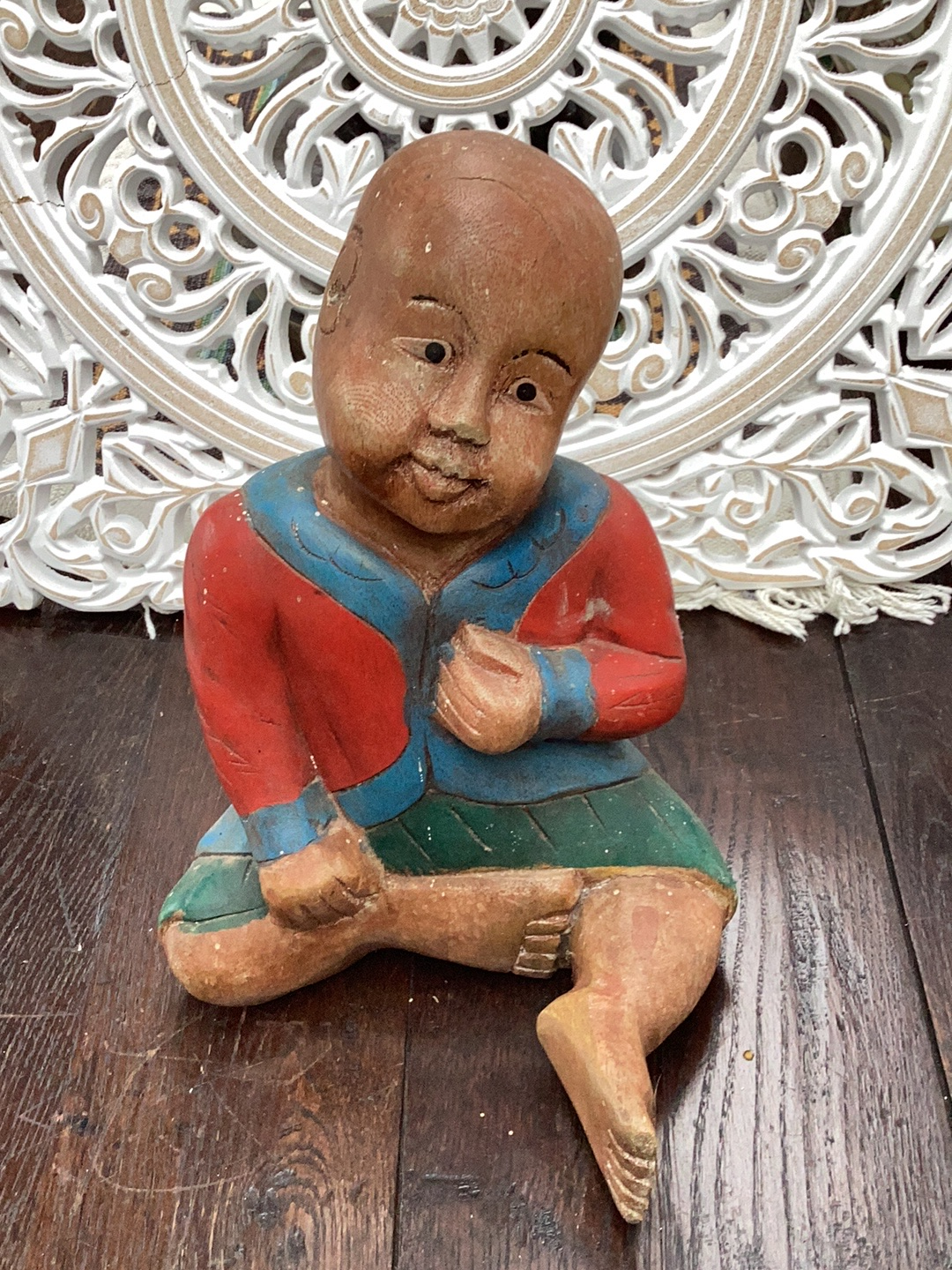 Wooden carved and painted figure of a seated child in traditional Asian attire