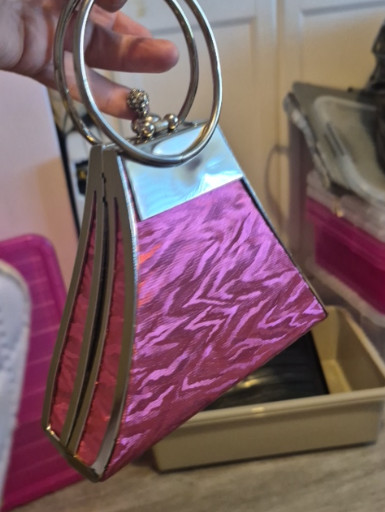 Contemporary metal-frame handbag with iridescent pink acrylic panels and circular handle