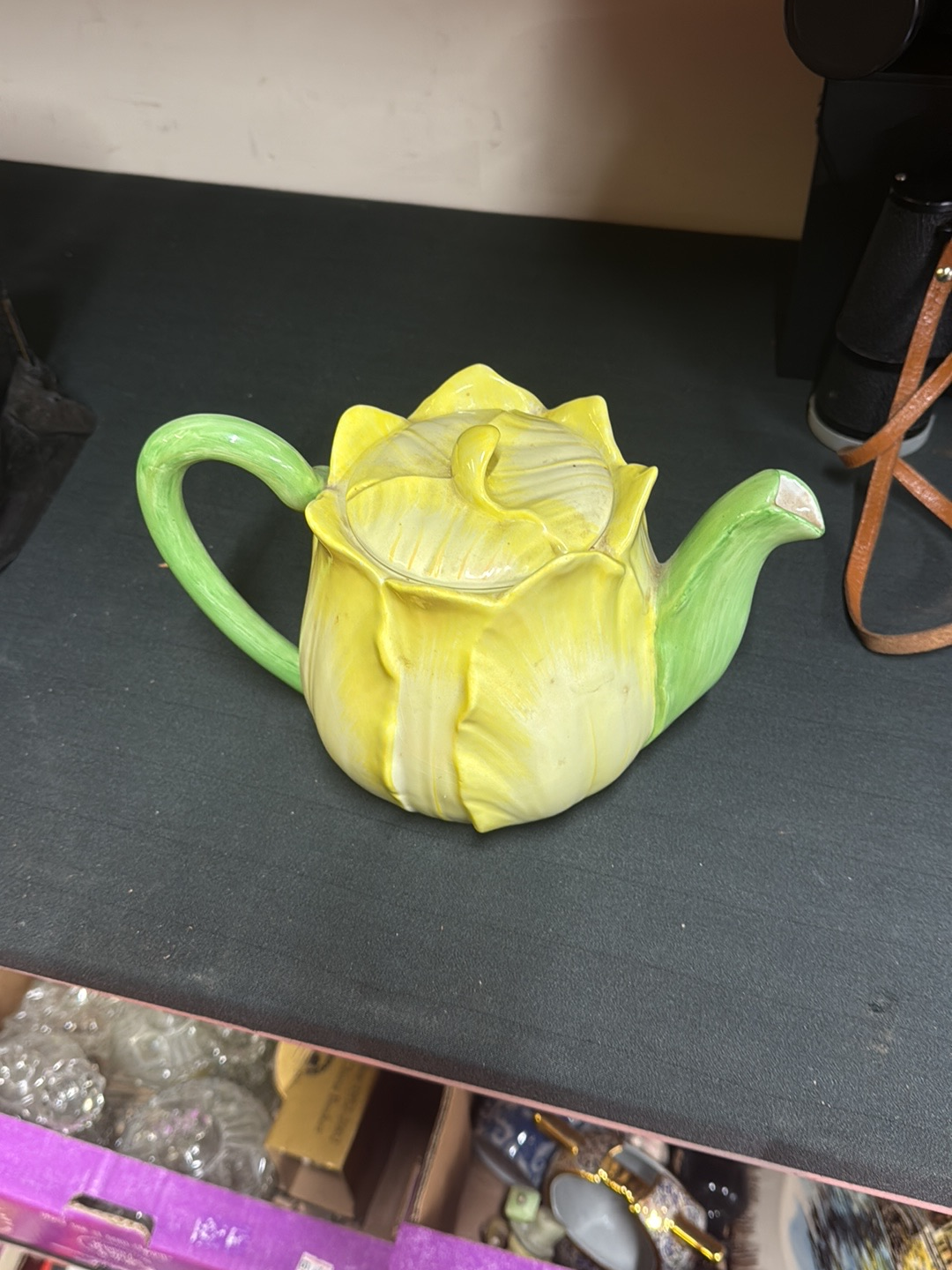 Ceramic teapot shaped as a yellow flower with green handle and spout