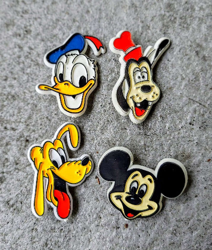 Set of four vintage plastic Disney character pins featuring Donald Duck, Goofy, Pluto, and Mickey Mouse